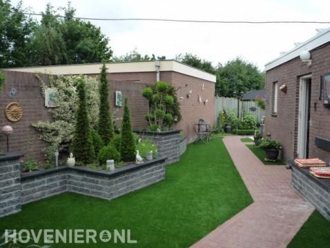 Achtertuin met terrasoverkapping, kunstgras en plantenbakken 2
