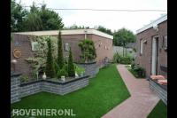 Achtertuin met terrasoverkapping, kunstgras en plantenbakken 2