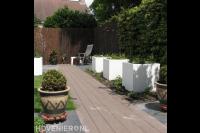 Witte bloembakken langs tuinpad van vlonderplanken