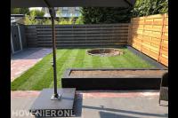 Tuinaanleg met bestrating, plantenbak en gazon met trampoline