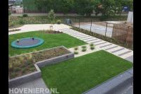 Moderne tuin met kunstgras en grindpad met stapstenen van natuursteen