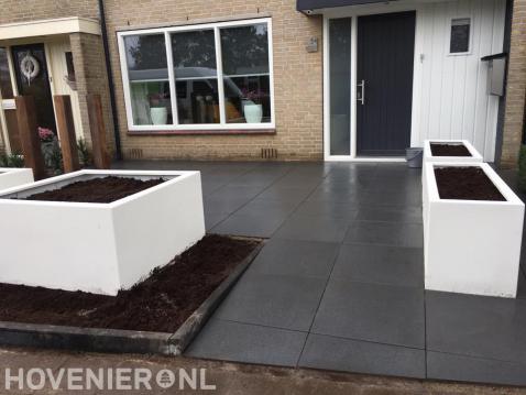 Moderne voortuin met grote siertegels en witte bloembakken