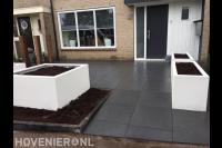 Moderne voortuin met grote siertegels en witte bloembakken