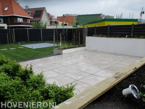 Moderne tuin met bestrating, witte plantenbakken en gazon