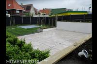 Moderne tuin met bestrating, witte plantenbakken en gazon