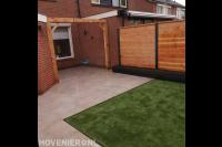 Tuinaanleg met sierbestrating, kunstgras, houten pergola en schutting