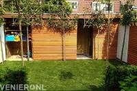 Kunstgras en leibomen voor houten berging