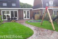 Achtertuin met grasgazon, schommel en ingebouwde trampoline