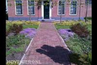 Voortuin met kleurrijke beplanting en leibomen