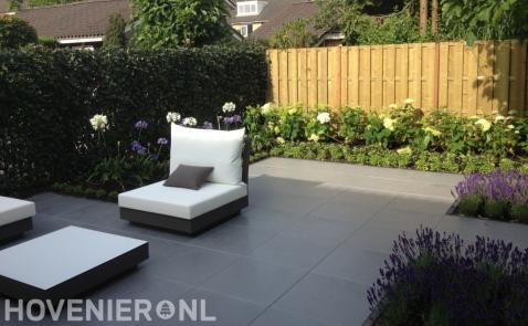 Moderne tuin met grote grijze tuintegels en kleurrijke borders 1