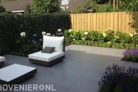 Moderne tuin met grote grijze tuintegels en kleurrijke borders 1