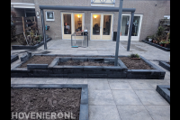 Tuinaanleg met sierbestrating, plantenbakken en terrasoverkapping