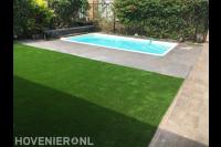 Tuin met kunstgras en bestrating rondom zwembad