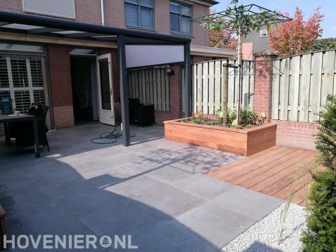 Achtertuin met bestrating, terrasoverkapping en houten vlonder