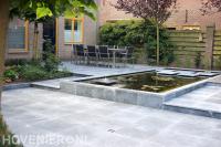 Achtertuin met bestrating en strakke vijver met fontein en stapstenen