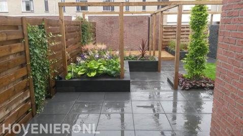 Achtertuin met vlonder, pergola en verhoogde borders van stapelblokken