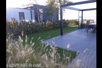 Terrasoverkapping boven terras van siertegels en gazon van kunstgras