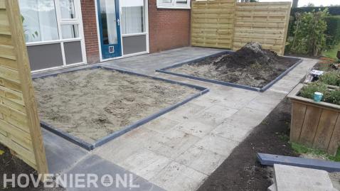 Achtertuin met bestrating, borders en houten schuttingen