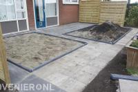 Achtertuin met bestrating, borders en houten schuttingen