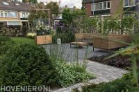 Terras van grote tuintegels met houten tafeltje en banken