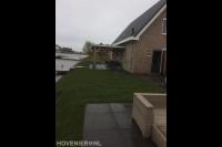 Tuin aan het water met gazon en terras met overkapping