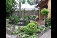 Tuin met houten overkapping, vlonder en vijver 1