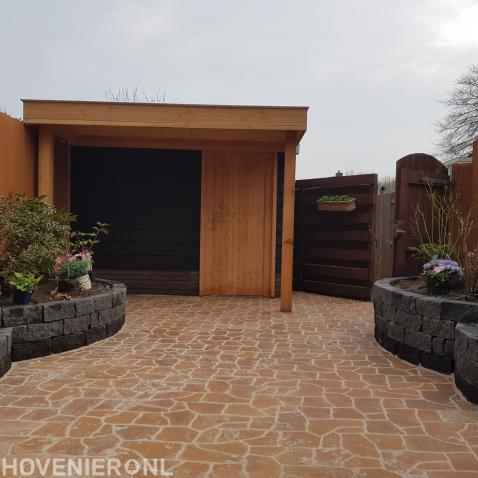 Houten schuurtje met overkapping en bestrating van flagstones