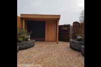 Houten schuurtje met overkapping en bestrating van flagstones