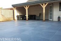 Houten overkapping met schuurtje en straatwerk van grote tegels