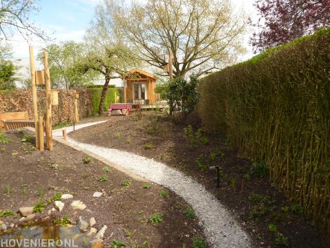 Smalle achtertuin met grindpad en houten tuinhuisje