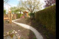 Smalle achtertuin met grindpad en houten tuinhuisje