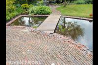 Vijver met vlonder en bestrating van waaltjes in vloeiende lijnen