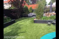 Tuinaanleg met terras, gazon van kunstgras en plantenbakken