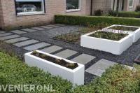 Onderhoudsarme voortuin met witte bloembakken en split met stapstenen