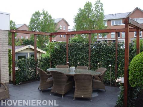 Terras omgeven door hardhouten pergola en klimop