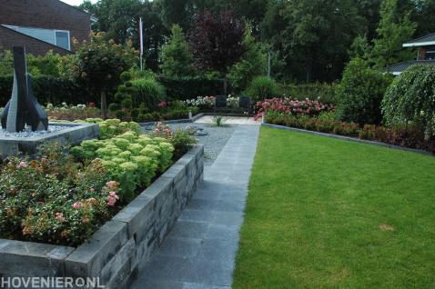Moderne tuin met gazon, verhoogde border en kleurrijke beplanting 1