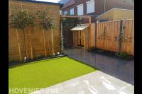 Tuinaanleg met sierbestrating, kunstgras en leibomen