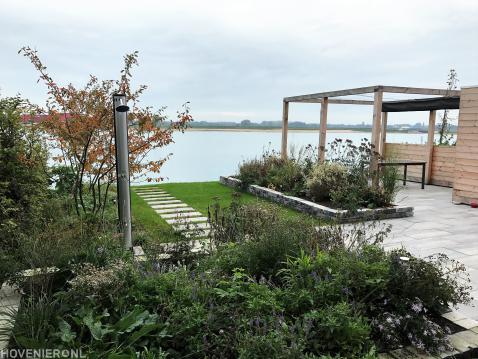 Tuin aan het water met gazon en pergola met harmonicadoek