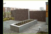 Onderhoudsarme achtertuin met grote tuintegels, split en schanskorf 2