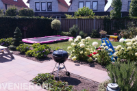 Kindvriendelijke achtertuin met bestrating, gazon en trampoline