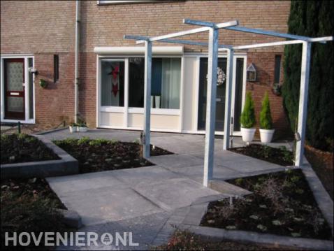 Voortuin met bestrating van grote tegels en pergola