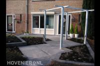 Voortuin met bestrating van grote tegels en pergola