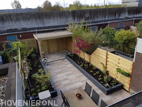 Achtertuin met bestrating, borders en houten overkapping