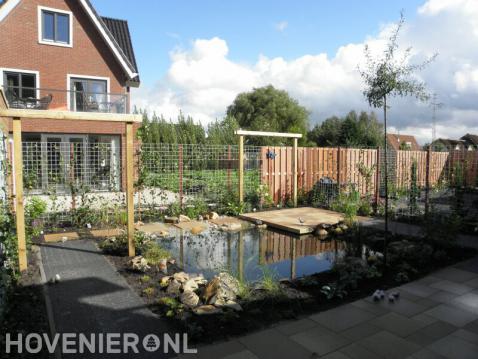 Tuin met vijver, pergola's en schutting van betongaas met klimop 2