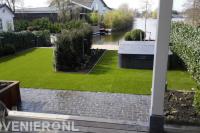 Moderne tuin aan het water met kunstgras en jacuzzi