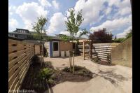 Tuinaanleg met bestrating, beplanting en houten schutting en pergola