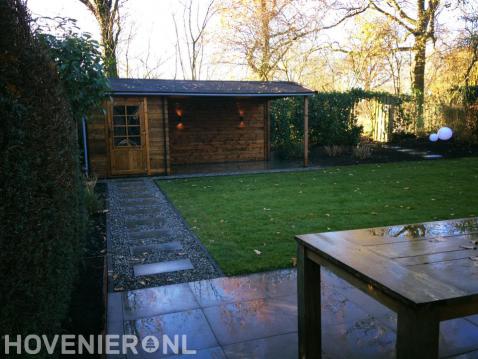 Tuin met terras, gazon en schuurtje met overkapping