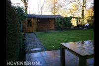 Tuin met terras, gazon en schuurtje met overkapping