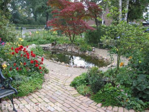 Vijver omgeven met grindpad en kleurrijke planten