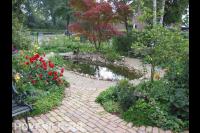 Vijver omgeven met grindpad en kleurrijke planten